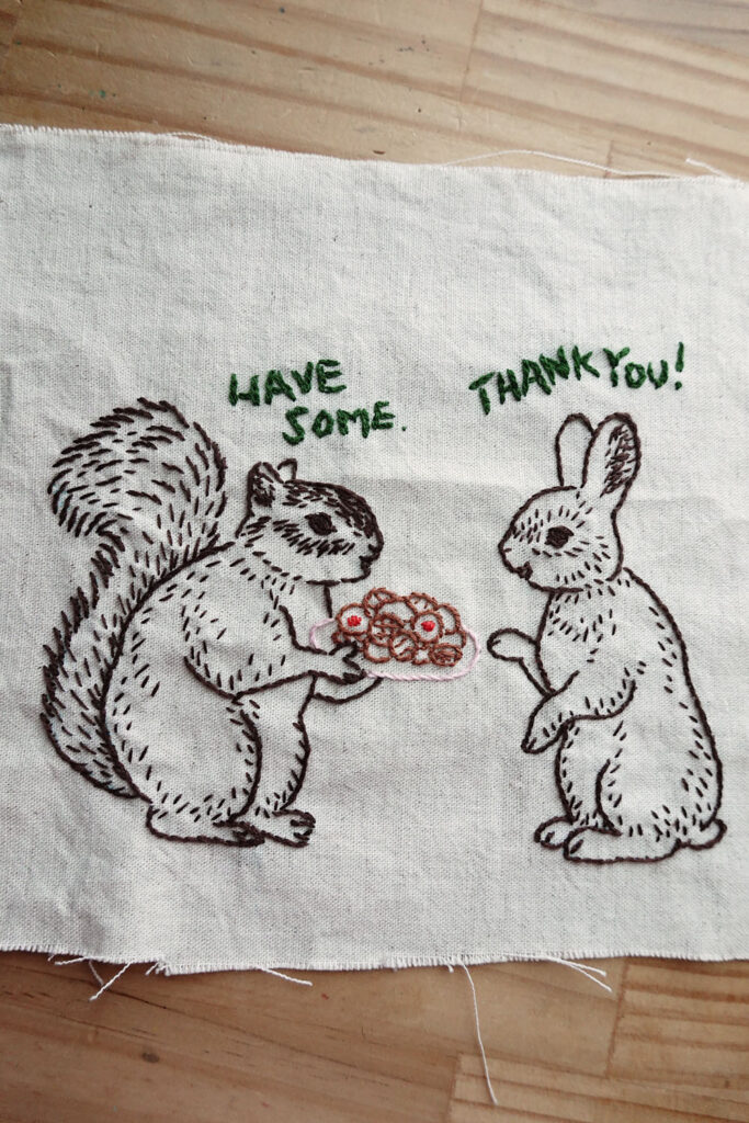 クッキーをのせた皿を持つリスと、それをもらおうとする、うさぎの絵の刺繍作品
