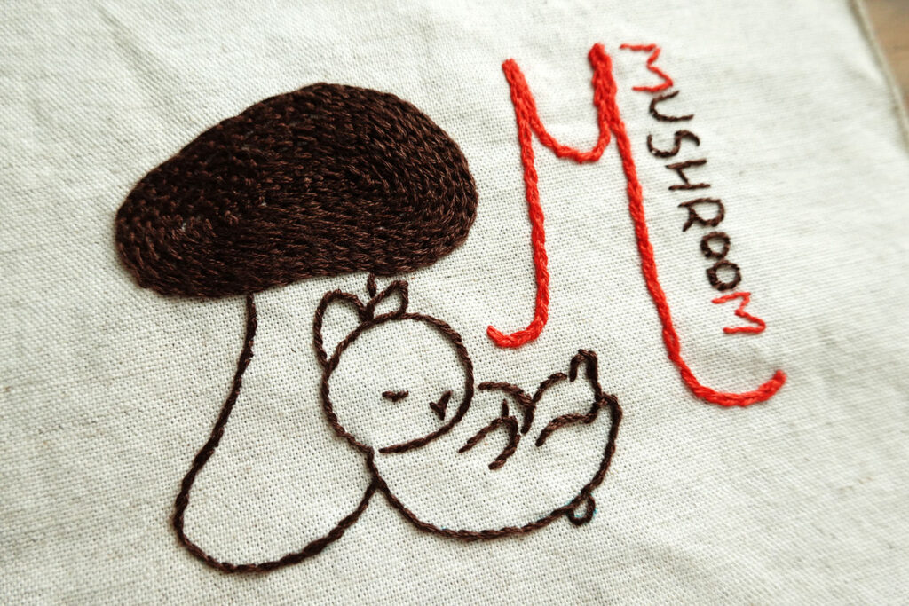 きのこに寄りかかって眠るうさぎの絵の刺繍作品