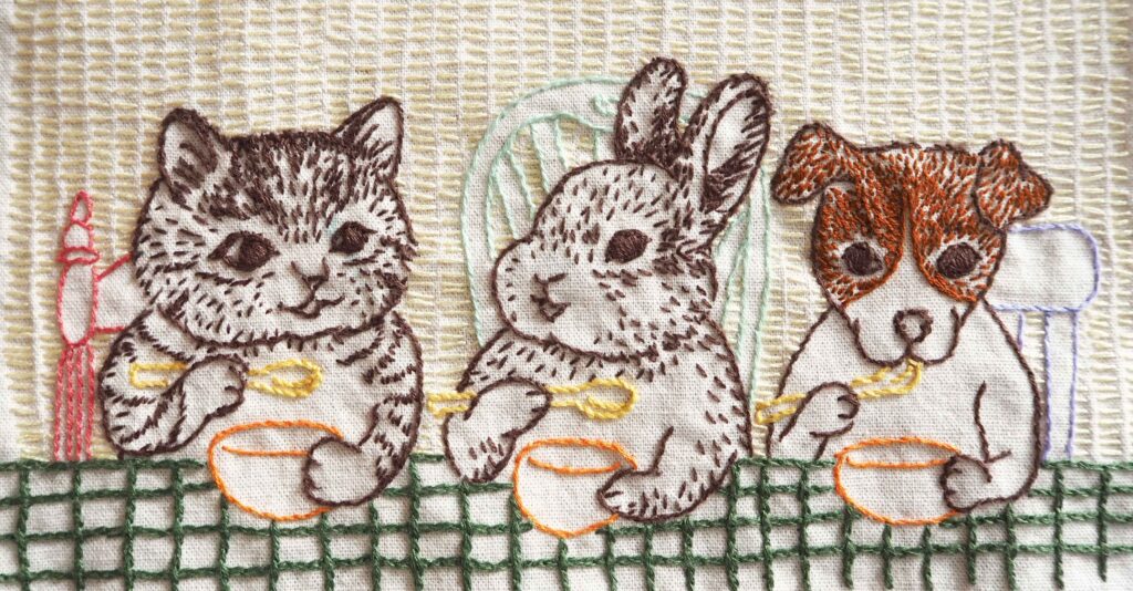 猫とうさぎと犬が食事をしている絵の刺繍作品